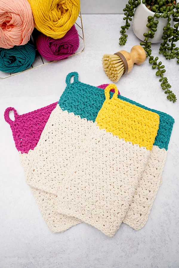 Two toned crochet dishcloths with hanging loops.