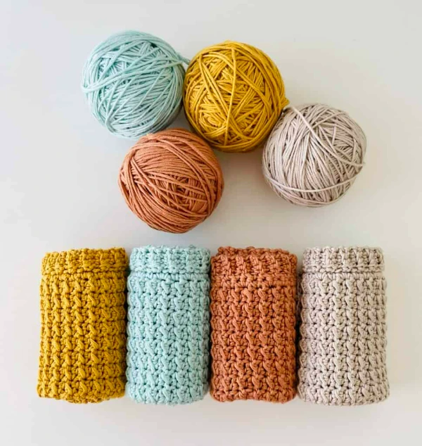 Four rolled-up crochet dishcloths with ribbed stitch borders