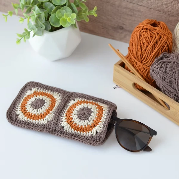 A brown and orange crochet granny square glasses case.