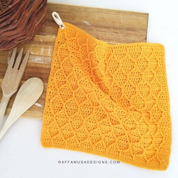 A yellow crochet dishcloth with raised honeycomb pattern.