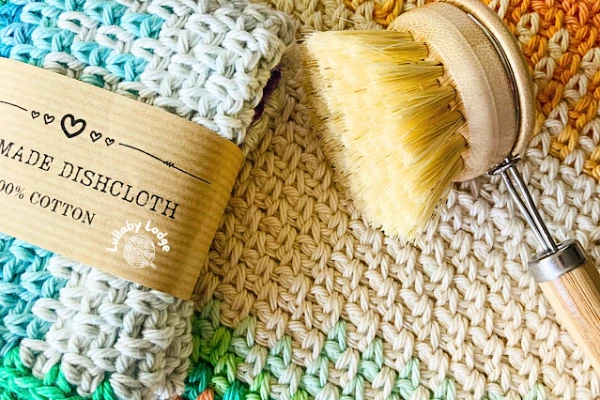 A linen stitch dishcloth and  a scrubbing brush.