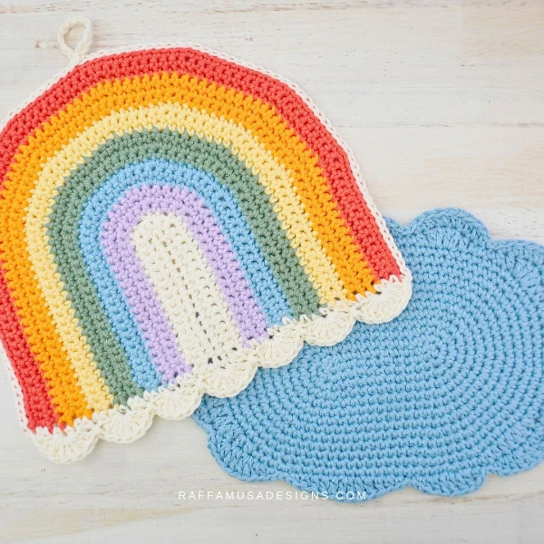 A rainbow shaped dishcloth and a cloud shaped dishcloth.