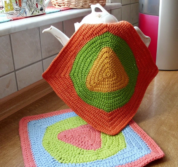 Brightly coloured crochet dishcloths with triangle motifs in the centres.