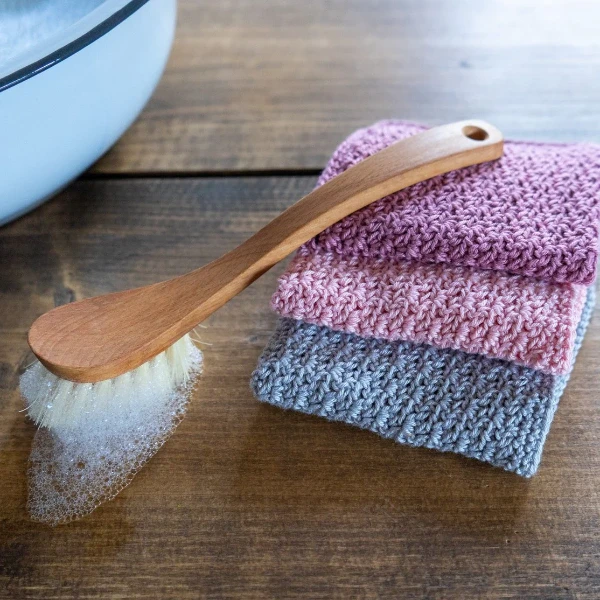 Three crochet dishcloths and a washing up brush.
