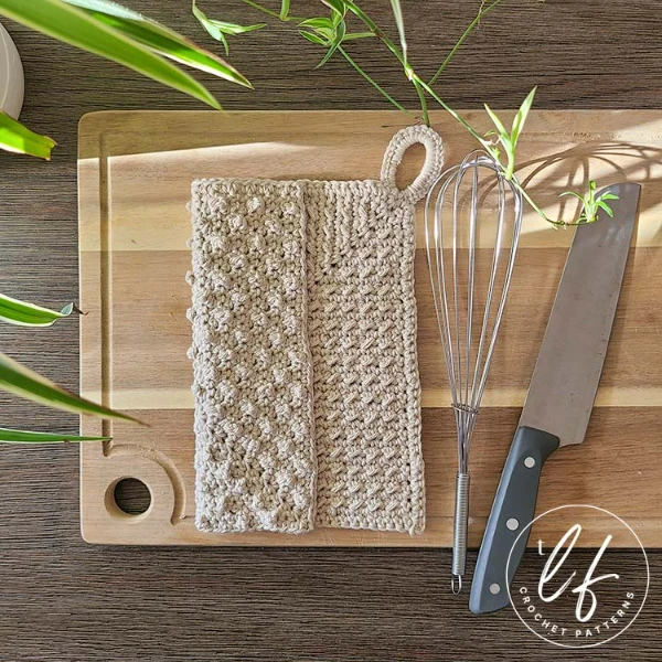 A mini bobble textured crochet dishcloth on a chopping board.