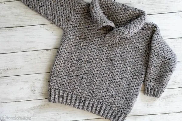 A grey child's crochet sweater with a collar.