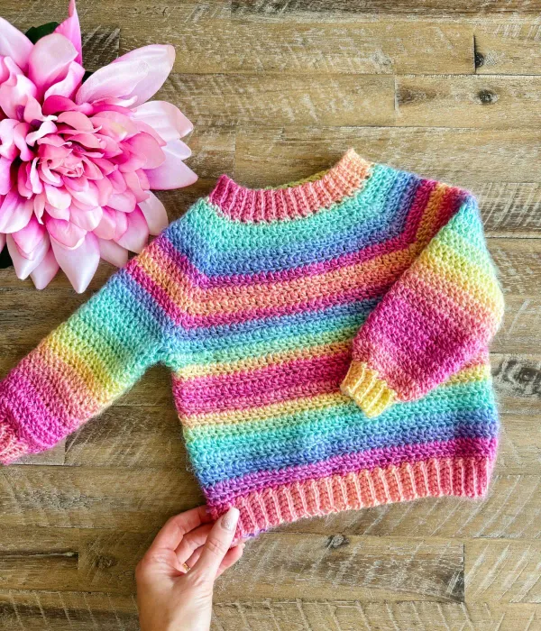 A rainbow-striped kids' crochet pullover.
