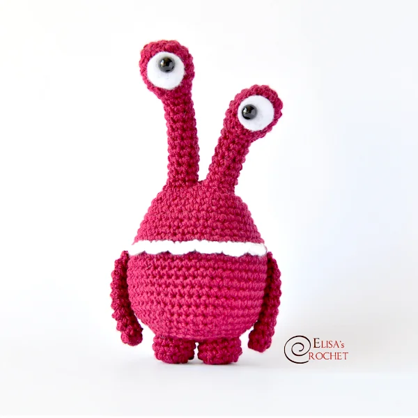 Pink crochet monster with long googly eyes.