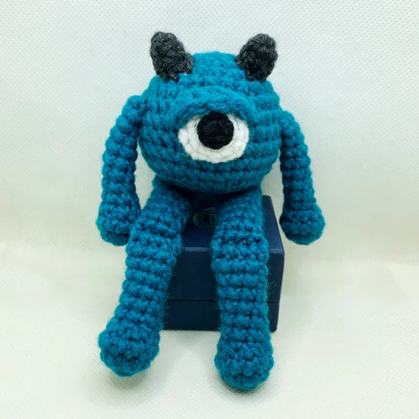 A blue one-eyed crochet mini monster.