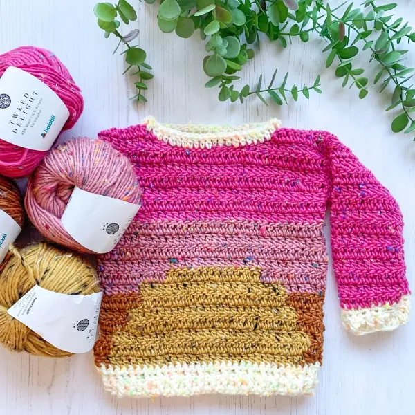 A handmade kid's crochet sweater with a sun motif.