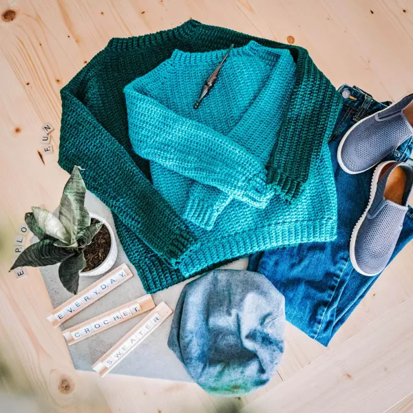 A flatlay image of two kids crochet sweaters.