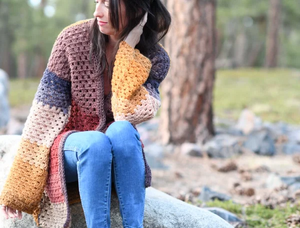 A woman wearing a granny stotch cardigan crocheted in self-striping yarn.