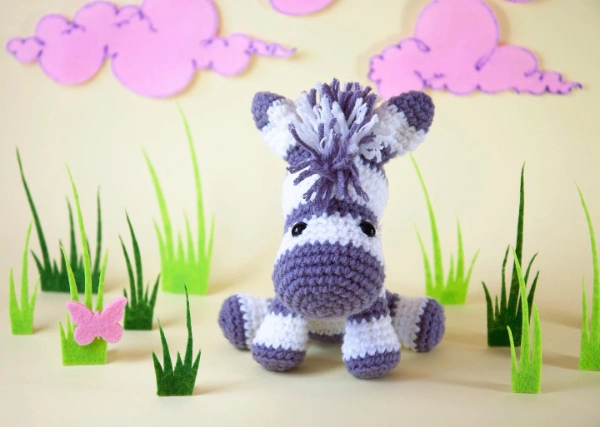 A grey and white crocheted zebra toy.